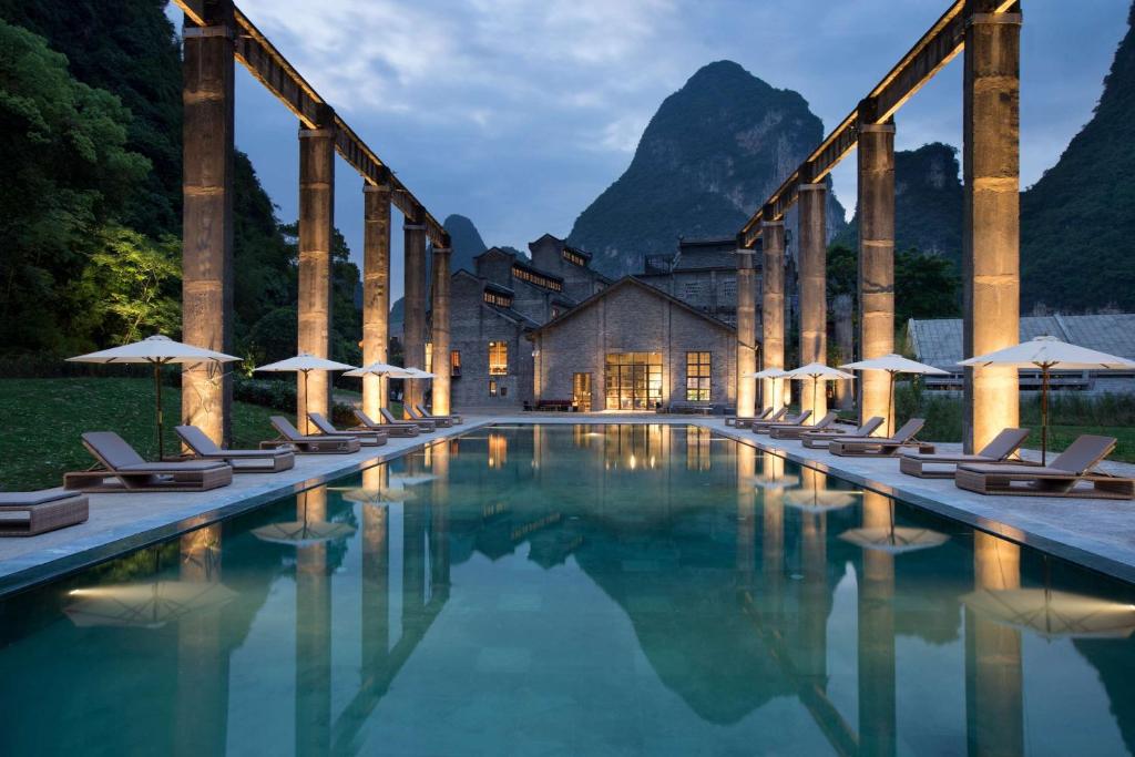 The concrete frames of a former sugar mill standing below karst hills on the Li River.