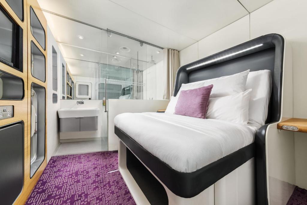 A compact airport cabin with a folding bed, a desk surface and adjustable lighting.